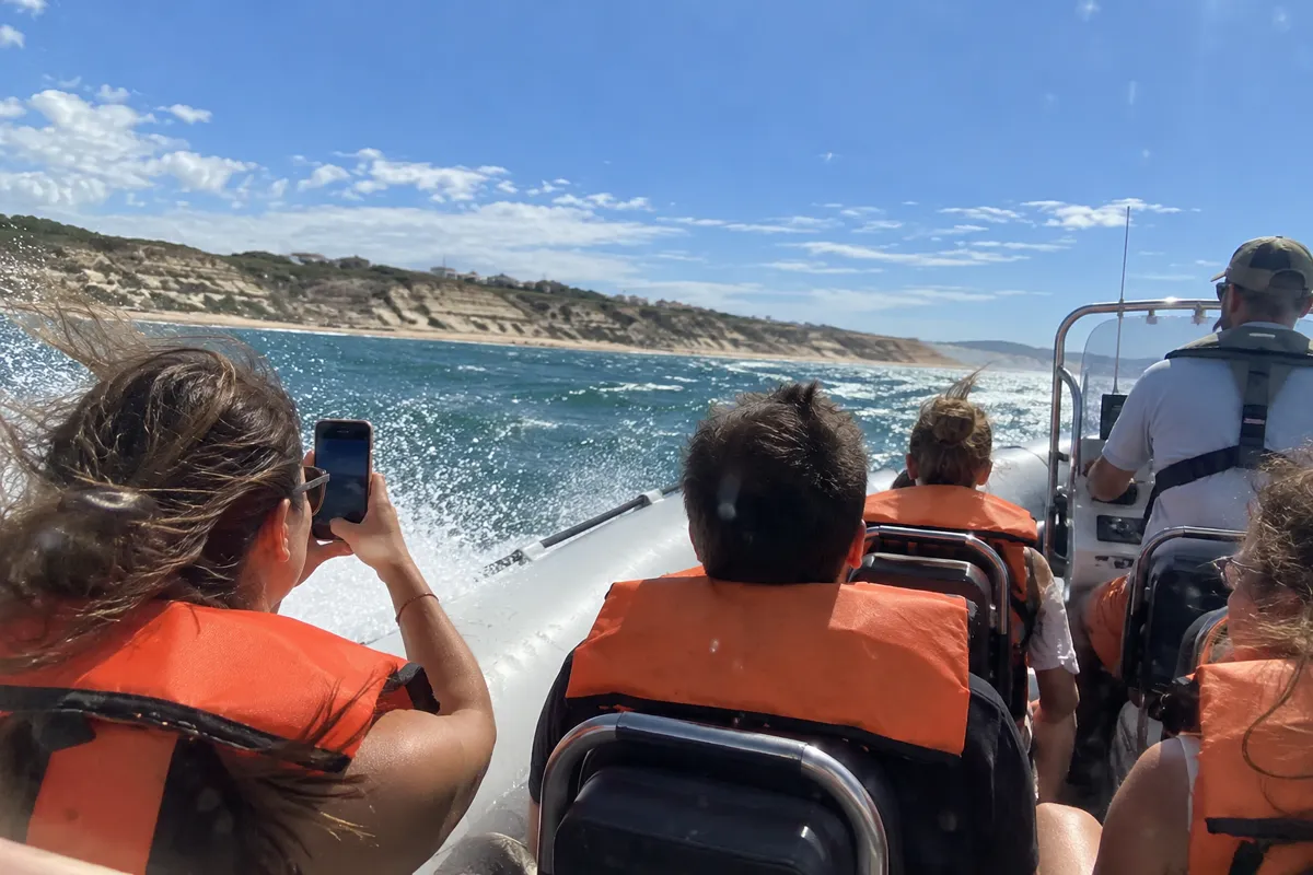 Turistas con chaleco salvavidas en una lancha por la costa